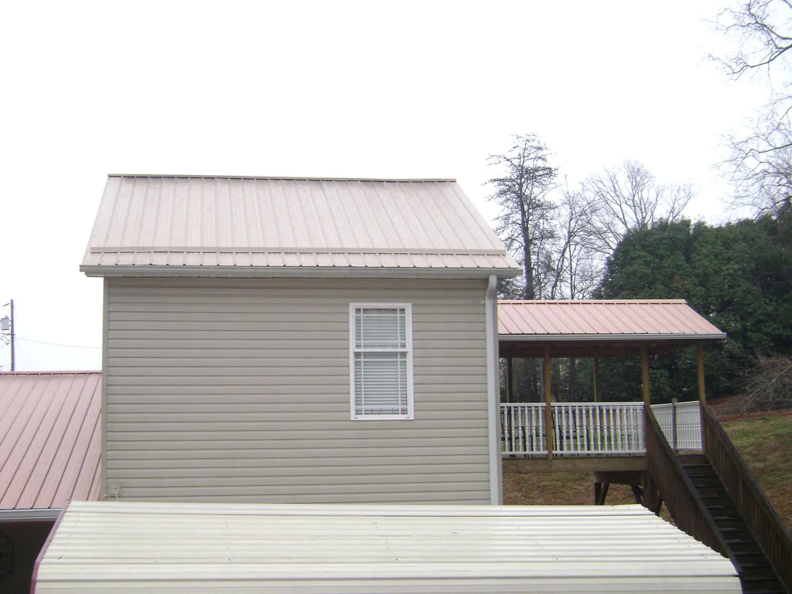 Tan metal roofs on a two story addition and attached porch, from a Roof Replacement job in Somerset